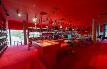 Interior of red room - floors and wall and shelving same colour. Table in centre of image.